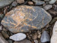 Dunkelgrauer Stein mit ockerfarbenen Linien und weißen Einschlüssen